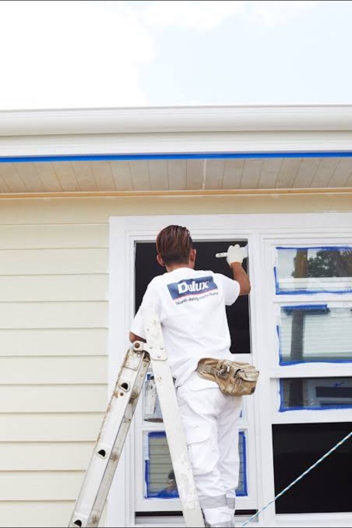 Professional painter applying a finish to exterior window trim